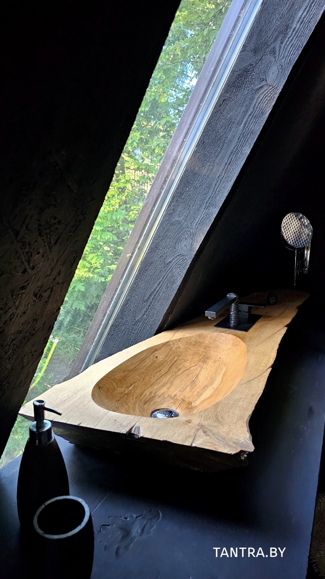 Ванная комната коттеджа A-Frame с раковиной из цельного дерева и панорамным окном в зелёный лес