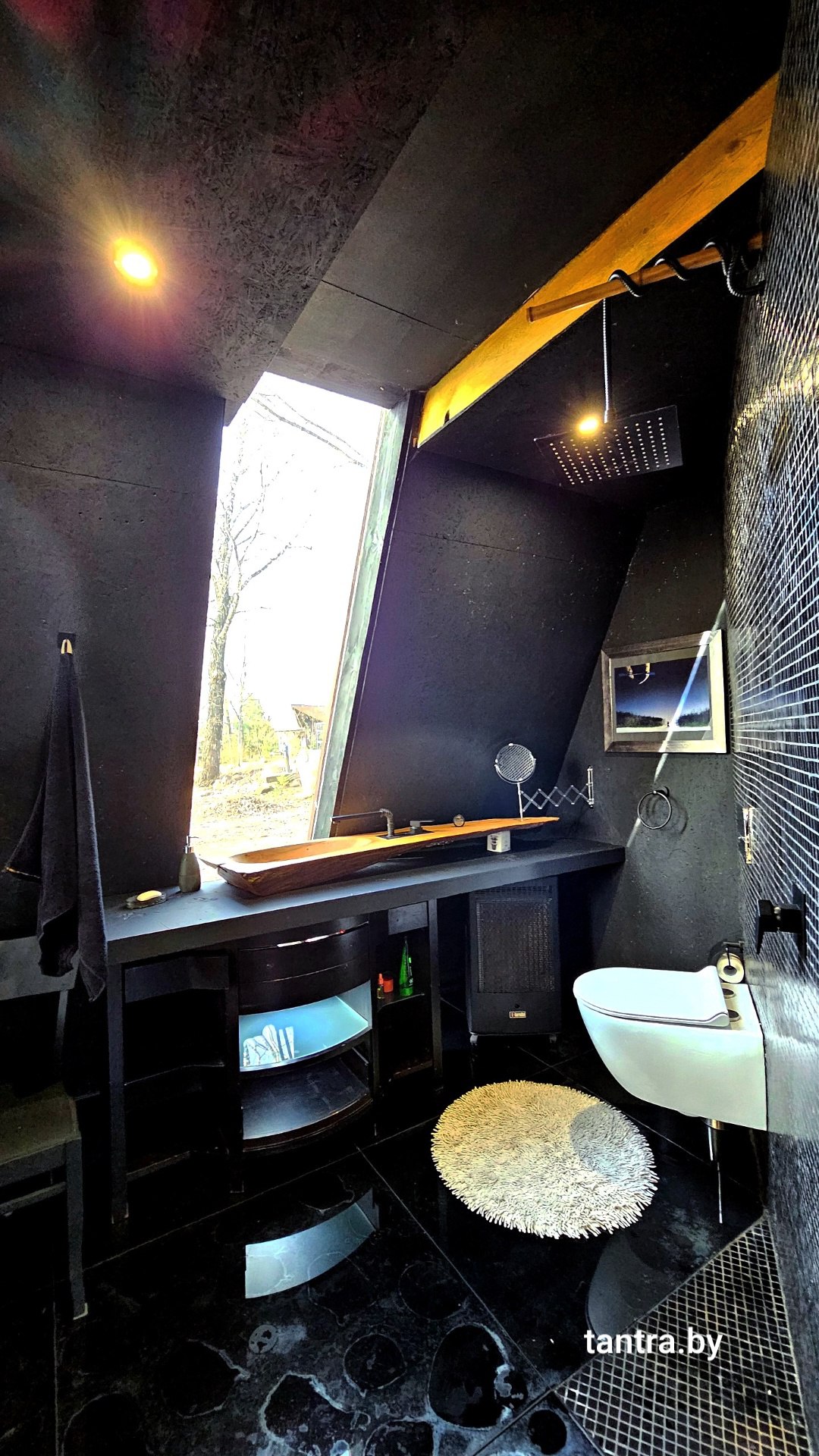 Чёрная ванная коттеджа A-Frame с раковиной из цельного дерева, тропическим душем и панорамным окном в лес